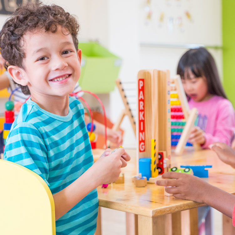 Smiling young boy playing with blocks in daycare